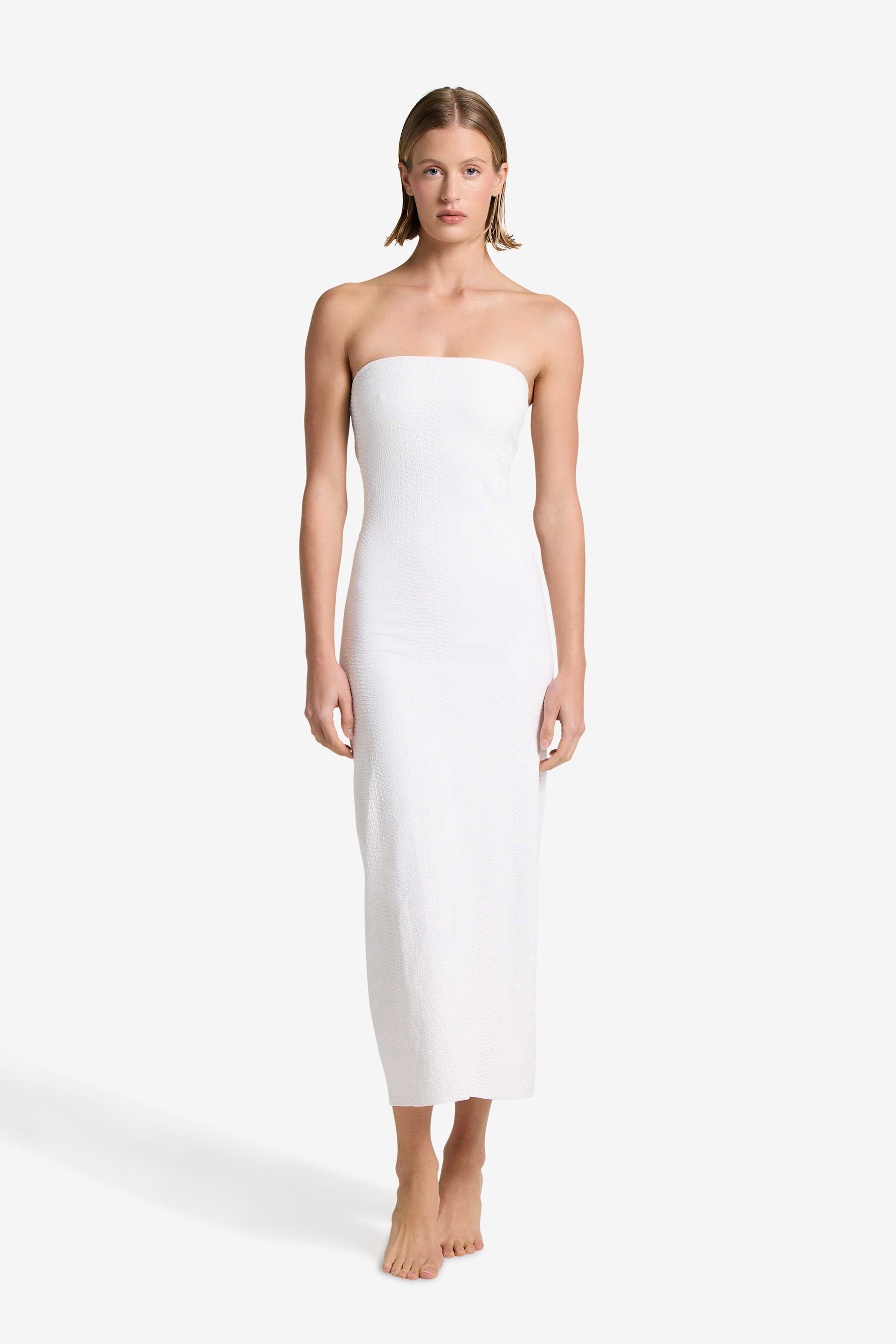 A person in the elegant Maya Dress by Gigi C Bikinis, featuring textured faux snake detailing, stands barefoot against a plain white background.