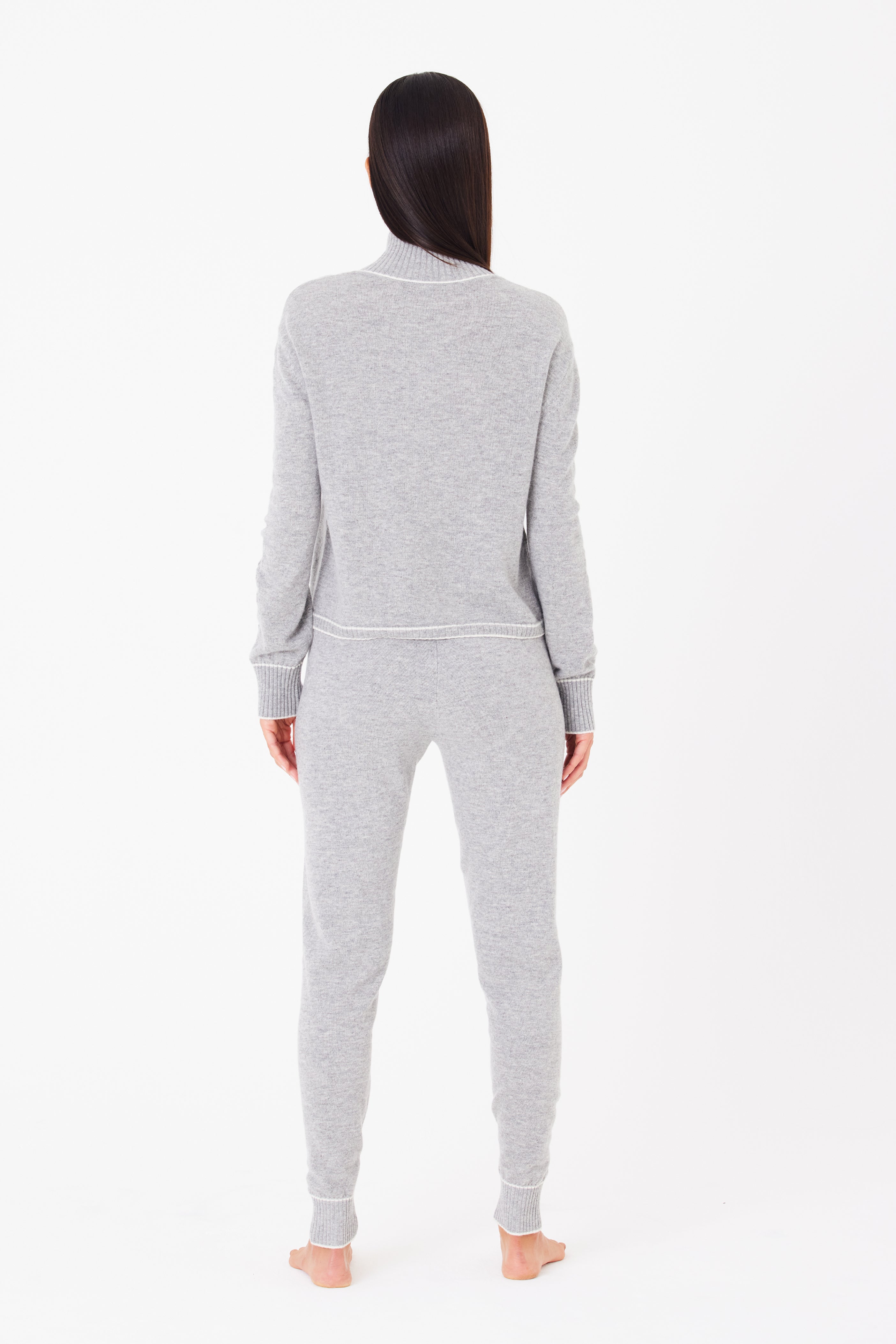 A person in a Gigi C Lounge Alice Jogger, made from a wool/cashmere blend, stands barefoot against a plain white background. Their hair is straight and dark.