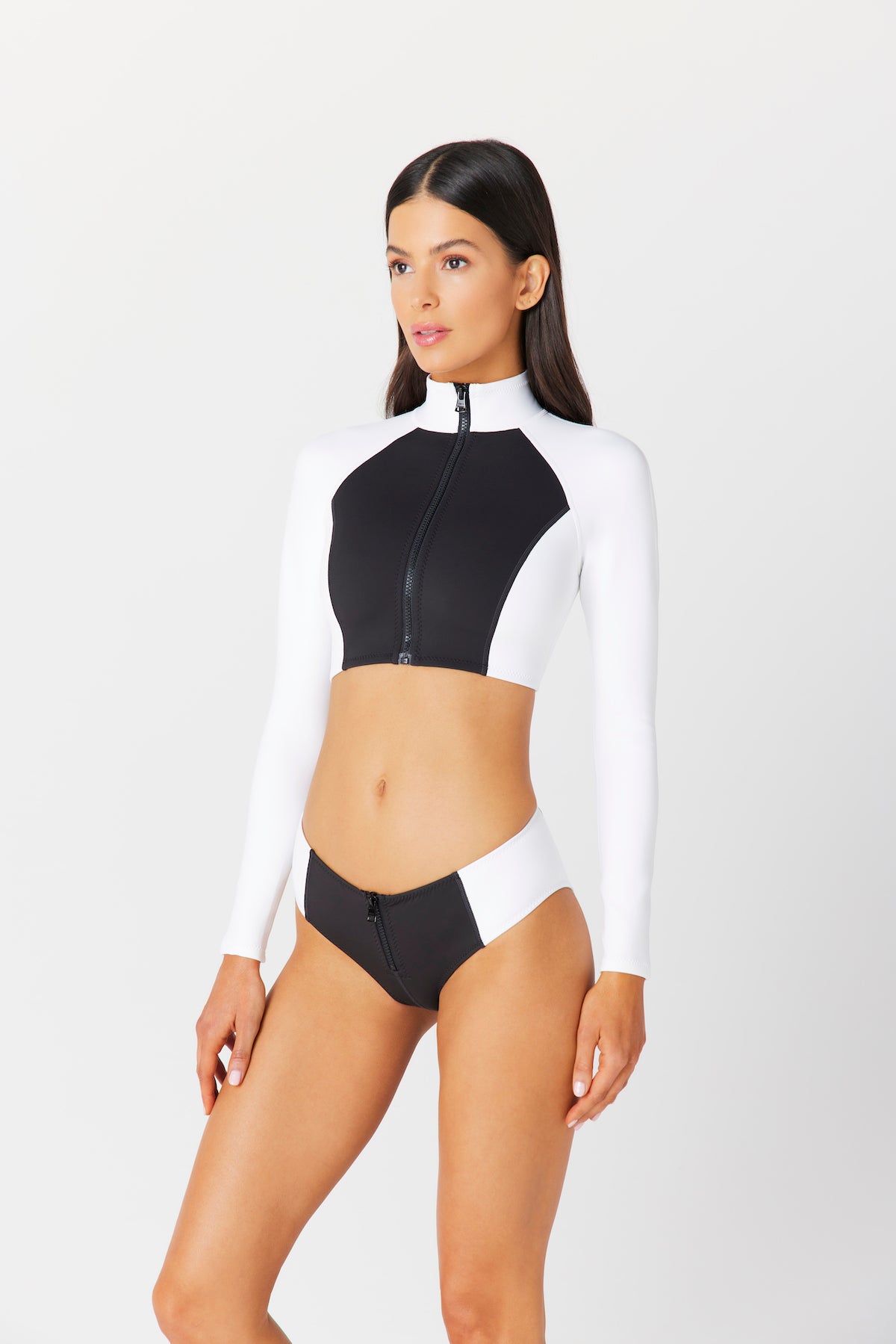 A woman models the black and white Missy Surf Jacket by Gigi C Bikinis, crafted from silky scuba fabric. She stands against a plain white background with straight hair and a neutral expression.